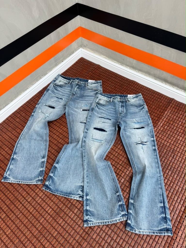 distressed, light-wash blue denim jeans with rip-and-repair patch details.